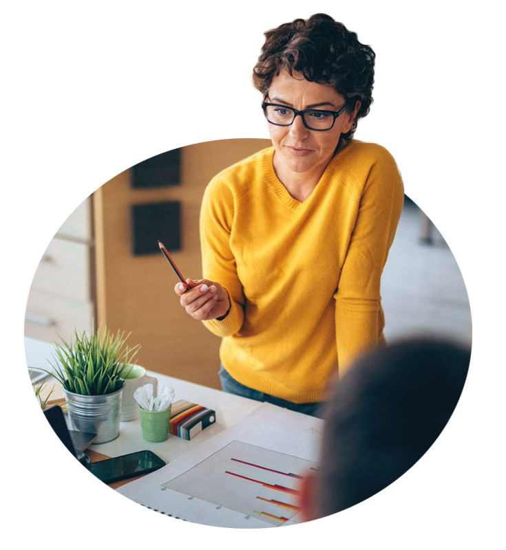 Woman in office in yellow sweater holding pencil